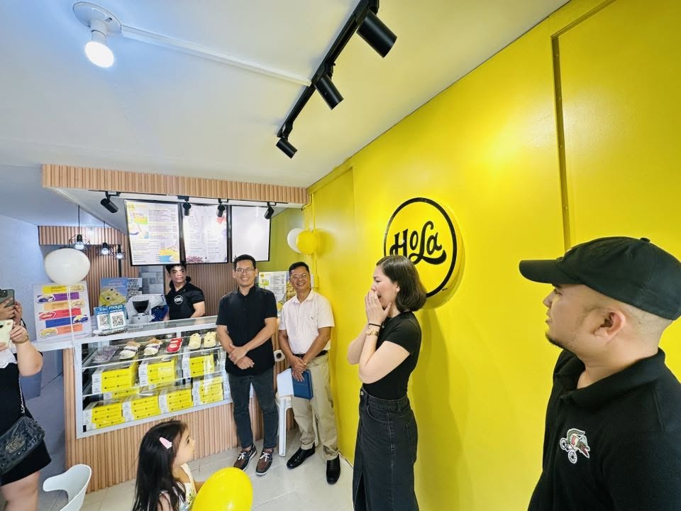 Inside a Hola branch — the sunrise-yellow Hola wall mark above the pastry display case